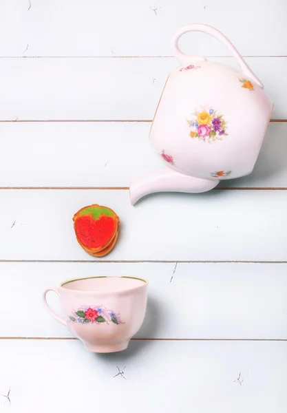 Tea cup soubory cookie jahody na modré dřevěné pozadí otrhaný šik romantické — Stock fotografie