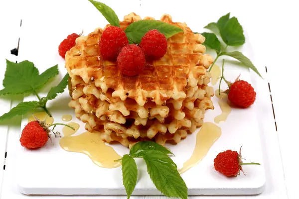 Pequeno-almoço waffles belgas com framboesas frescas cobertas com mel sobre fundo de madeira branca — Fotografia de Stock