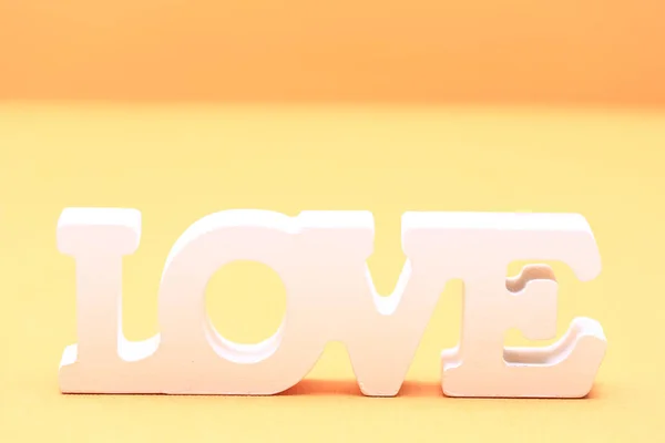 Valentine day love concept. Word love made from wooden letters on yellow paper background