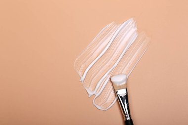 Kozmetik doğal pastel kavramı. Bej arka planda kozmetik fırçalı sıvı kremin dokusu. Temel makyaj. Çok yumuşak seçici odak