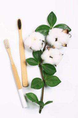 Kozmetik doğal pastel banyo konsepti. Duş için aksesuarlar ve pamuk çiçekli vücut bakımı. Beyaz arka planda bambu ahşap diş fırçaları