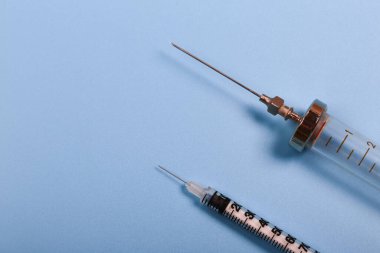 Tıbbi konsept. Mavi arka planda enjeksiyon için iki şırınga. İnsülin ve retro demir şırınga.