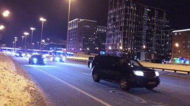 Kışın bir gece şehrinde arabalar karlı bir yol boyunca gider. Rusya Moskova 17.02.2021