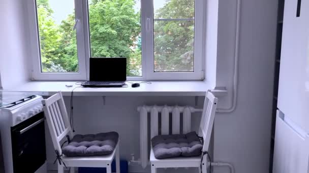 Apartament w kolorze białym z dużymi oknami. Mała biała kuchnia z laptopem na parapecie. — Wideo stockowe