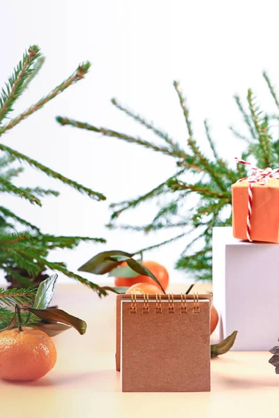 Christmas composition with spruce, tangerines, podium and notepad. Soft selective focus. Winter festive background — Stock Photo, Image