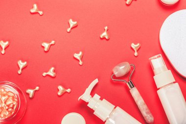 Pembe kozmetik arka plan, tekerlekli masaj aleti ve kapsüller. Yumuşak seçici odak.