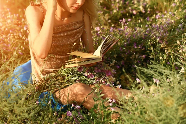 Jonge vrouw leest een boek in het veld in de natuur. zomeravond — Stockfoto
