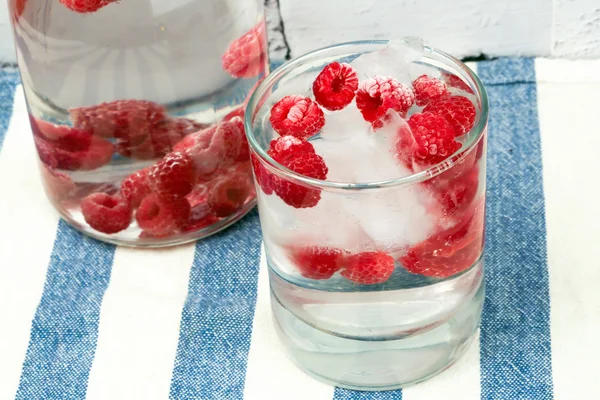 Cold water with frozen raspberries and ice summer hot — ストック写真