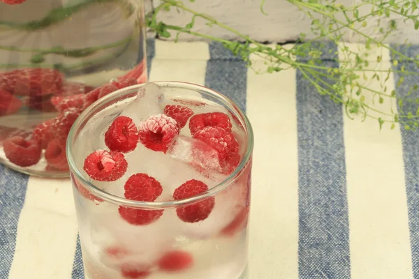 Cold water with frozen raspberries and ice summer hot — ストック写真
