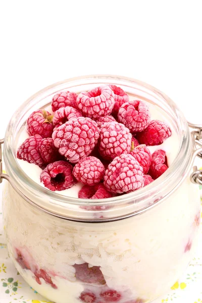 Beyaz zemin üzerinde bir cam kavanoza dondurulmuş ahududu ile kahvaltı pirinç tatlısı