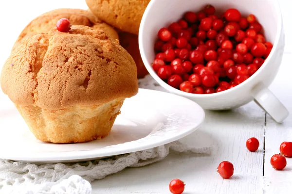 Muffiny s brusinkami na dřevěné bílé pozadí selektivní zaměření pečivo — Stock fotografie