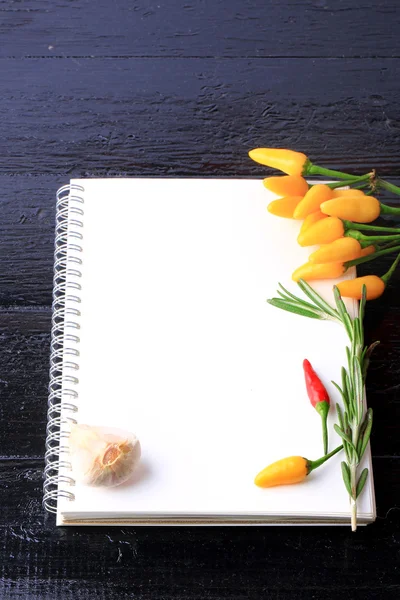 Täcka kokbok anteckningsbok på en svart trä bakgrund kryddor recept på vitlök timjan peppar — Stockfoto