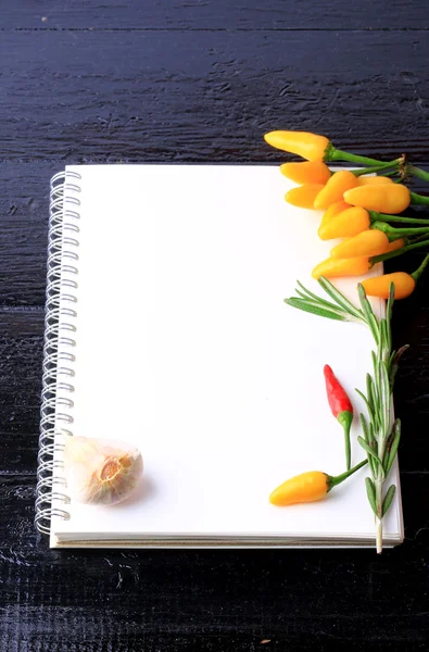 Täcka kokbok anteckningsbok på en svart trä bakgrund kryddor recept på vitlök timjan peppar — Stockfoto