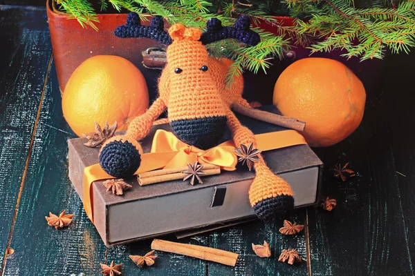 Christmas composition deer gift under the tree by hand knitted toy cinnamon, anise tangerine spruce vintage style on old wooden background — Stock Photo, Image