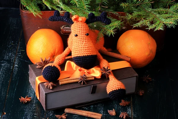 Christmas composition deer gift under the tree by hand knitted toy cinnamon, anise tangerine spruce vintage style on old wooden background — Stok fotoğraf