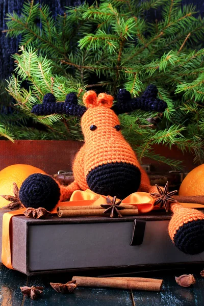 Christmas composition deer gift under the tree by hand knitted toy cinnamon, anise tangerine spruce vintage style on old wooden background — Stock Photo, Image