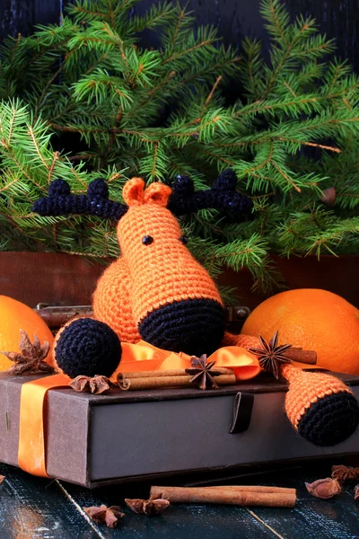 Christmas composition deer gift under the tree by hand knitted toy cinnamon, anise tangerine spruce vintage style on old wooden background — Stock Photo, Image