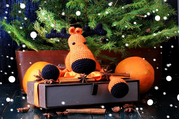 Christmas composition deer gift under the tree by hand knitted toy cinnamon, anise tangerine spruce vintage style on old wooden background — Stock Photo, Image