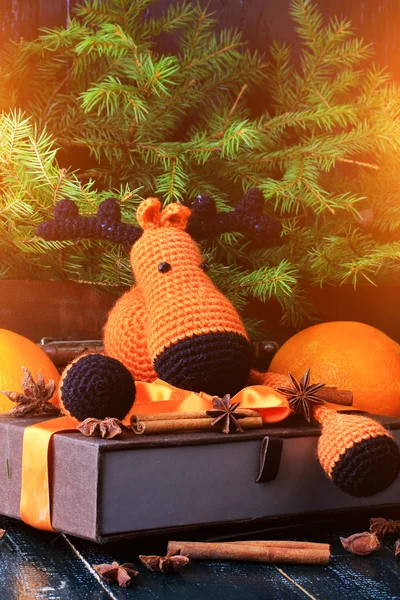 Рождественская композиция олень подарок под елкой вручную вязаной игрушкой корицы, анисовый мандарин ели винтажный стиль на старом деревянном фоне — стоковое фото