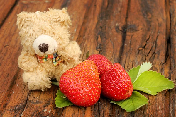 旧的木制背景上的草莓玩具熊。 — 图库照片
