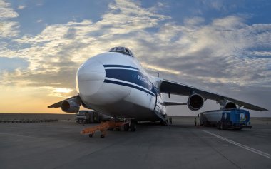 Dünyanın en büyük kargo uçağı An-124-100 Ruslan (Rusya) havaalanında Al Ain (Birleşik Arap Emirlikleri, Bahar 2013), bulutlar ve yükselen güneşin arka plan üzerinde dolumu.