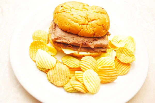 Сэндвич со стейком и сыром на луковом рулете с овощными чипсами — стоковое фото