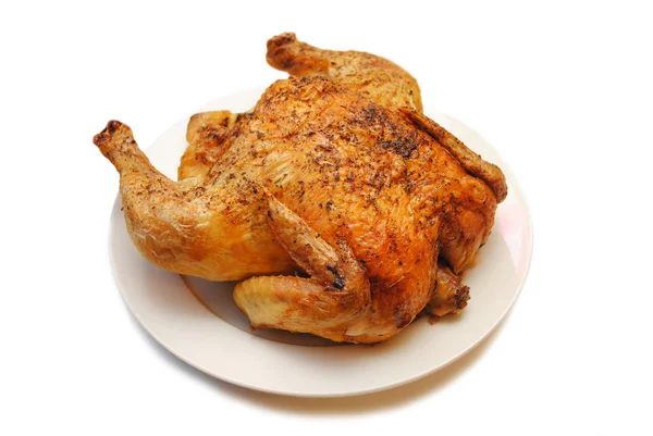 Целый жареный цыпленок на круглом белом блюде — стоковое фото
