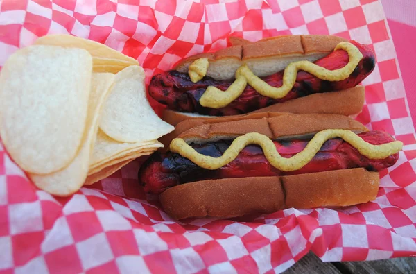 Deux hot-dogs rouges à emporter servis avec des chips de moutarde et de pomme de terre — Photo
