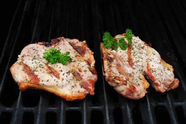 Dos chuletas de cerdo perfectamente cocidas en una parrilla adornada con perejil fresco —  Fotos de Stock