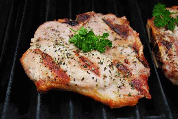 A Perfectly Cooked Pork Chop on a Grill Garnished with Fresh Parsley