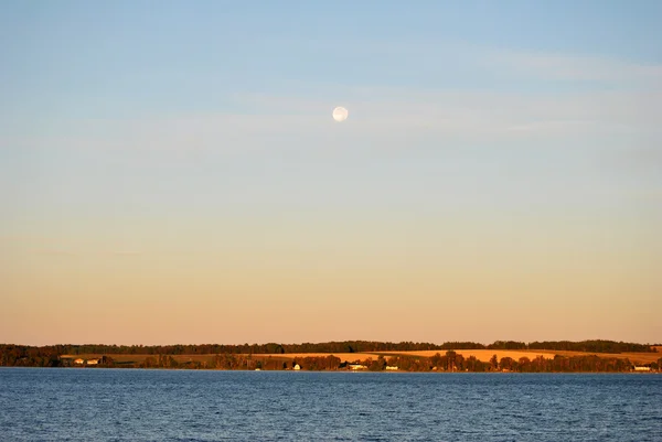 Una luna llena brillante en el cielo durante un amanecer — Foto de Stock