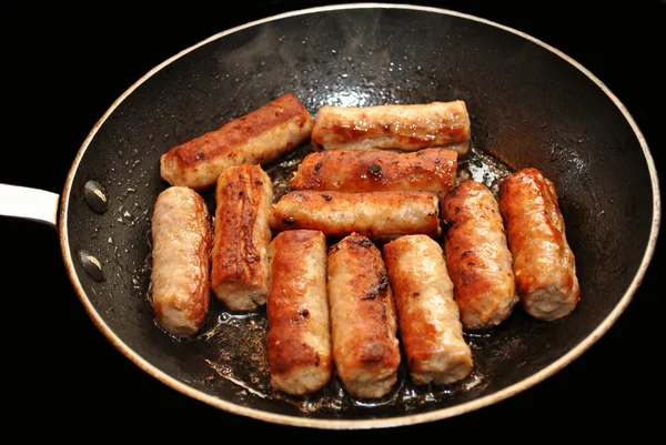 Embutidos marrones crujientes cocinando en una sartén —  Fotos de Stock