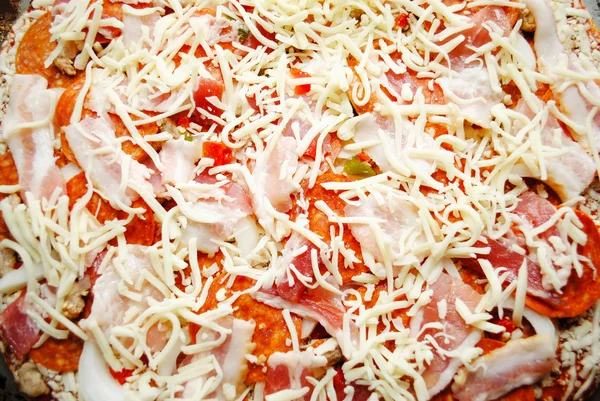 Pastel crudo de pizza con queso, pepperoni y tocino — Foto de Stock