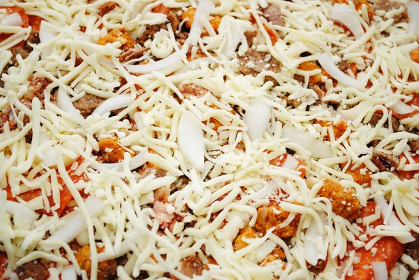Ongekookt Cheesy, vlezige Pizza cirkel bedekt met kaas — Stockfoto