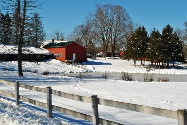 Een besneeuwde schuur op een boerderij met een houten hek — Stockfoto