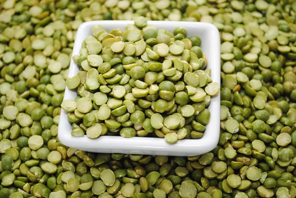 Diviser les pois verts dans un bol carré sur un fond de pois — Photo