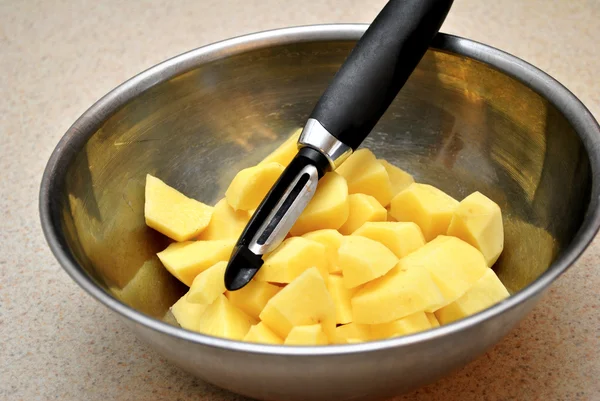 Stål skål med potatis och en potatisskalare — Stockfoto