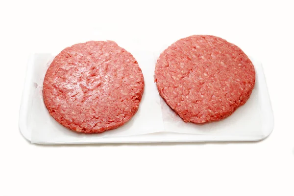 Galettes de hamburger crues sur un plateau en mousse — Photo