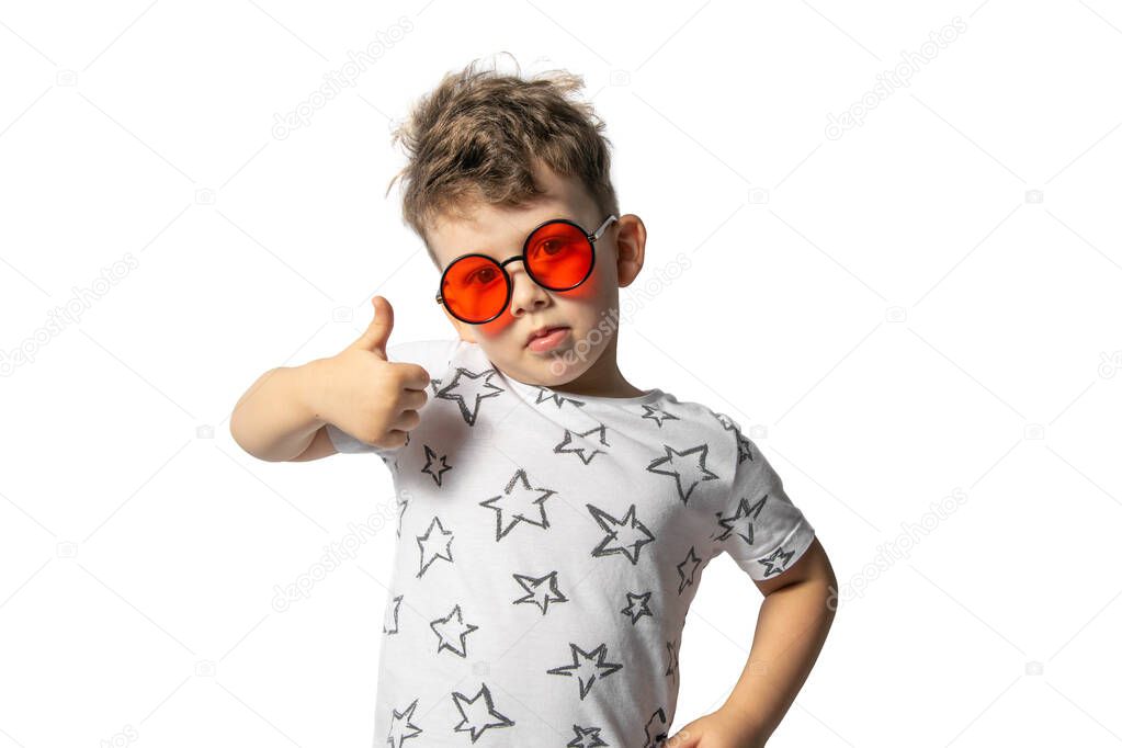 A beautiful caucasian boy in red glasses with curly hair on a white background shows the class. Super. Isolated