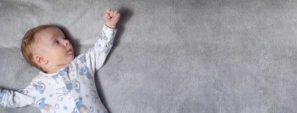 Pequeno bebê branco recém-nascido em um fundo cinza com espaço para texto — Fotografia de Stock