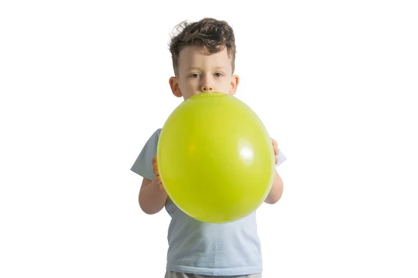 Funny boy blowing up a yellow balloon isolated on white background Stock Picture