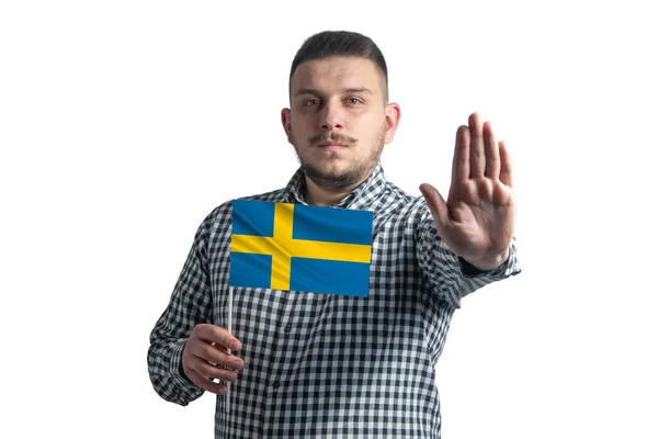 Biały facet trzymający flagę Szwecji i z poważną twarzą pokazuje znak stopu dłoni odizolowany na białym tle — Zdjęcie stockowe