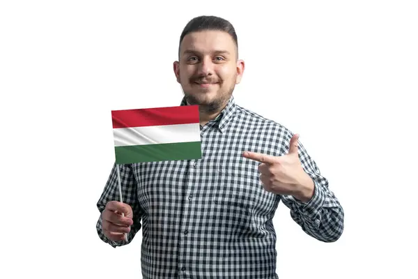 Cara branca segurando uma bandeira da Hungria e aponta o dedo da outra mão para a bandeira isolada em um fundo branco — Fotografia de Stock