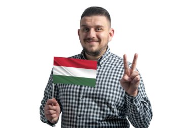 Beyaz adam elinde Macaristan bayrağı tutuyor ve beyaz arka planda iki parmak gösteriyor..
