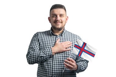 Beyaz adam Faroe Adaları 'nın bayrağını tutuyor ve elini kalbinin üstünde tutuyor beyaz bir arka planda Faroe Adaları' na sevgilerle..