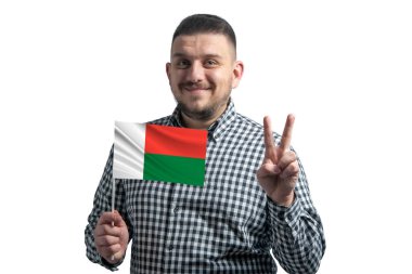 Madagaskar bayrağı taşıyan beyaz bir adam beyaz bir arka planda iki parmak gösteriyor..