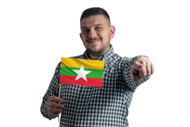 Beyaz adam elinde Myanmar 'ın bayrağını tutuyor ve beyaz bir arka planda tek başına önünü işaret ediyor..