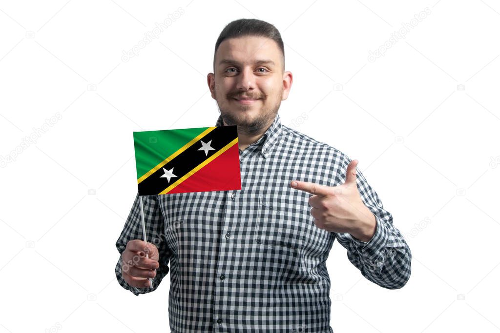 White guy holding a flag of St. Kitts and Nevis and points the finger of the other hand at the flag isolated on a white background.