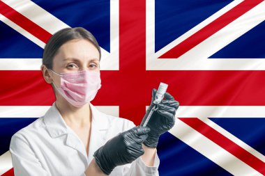 Kız doktor, Birleşik Krallık bayrağının arka planına karşı aşı hazırlıyor. Aşı kavramı Birleşik Krallık.