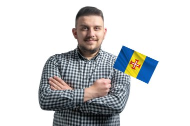 Beyaz adam Madeira 'nın bayrağını tutuyor. Beyaz bir arka planda kollarını kavuşturup gülümsüyor..